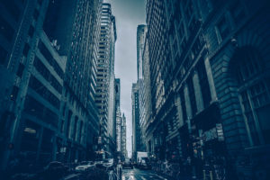 A city street with tall buildings and cars driving down it.