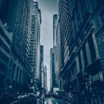 A city street with tall buildings and cars driving down it.